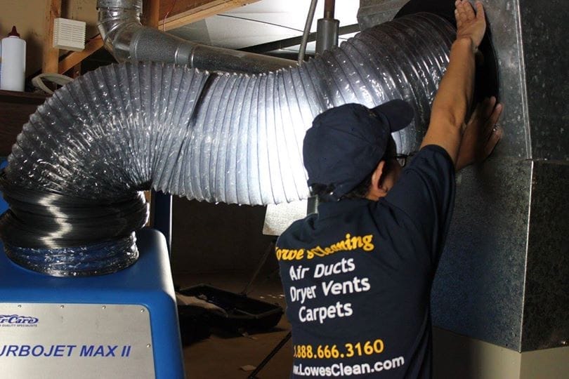 Lowe's Air Duct Cleaning technician connecting negative-pressure equipment to ductwork in Orlando